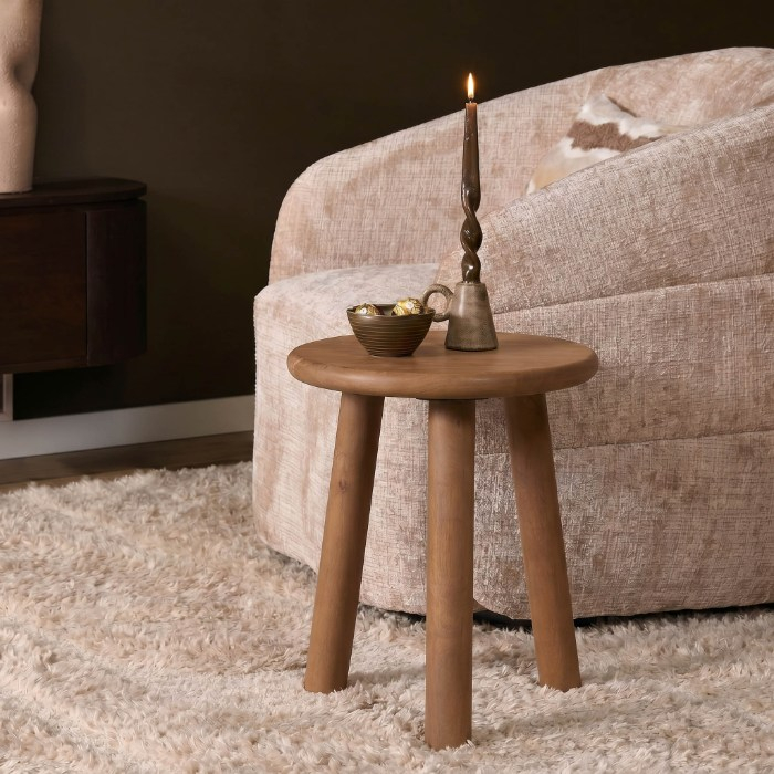 Rond houten bijzettafeltje Enzo walnoot naast een beige fauteuil op een vloerkleed