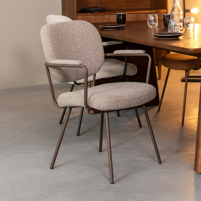Eetkamerstoel Loek in grijs bouclé met bronzen frame aan de eettafel