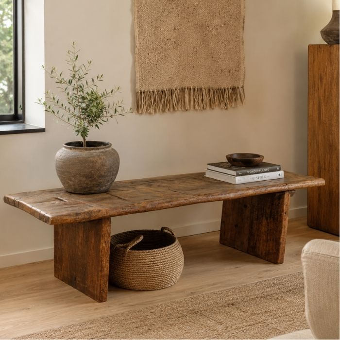 Houten bankje uit India, gestyled als salontafel in een lichte woonkamer met plant en mand
