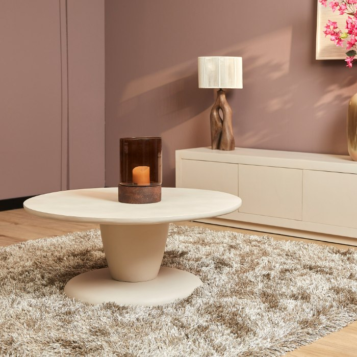 Ronde zandkleurige salontafel Mabel van mangohout met sculpturale voet in de woonkamer