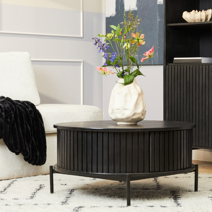 Zwarte ronde salontafel Madison van mangohout op een licht vloerkleed