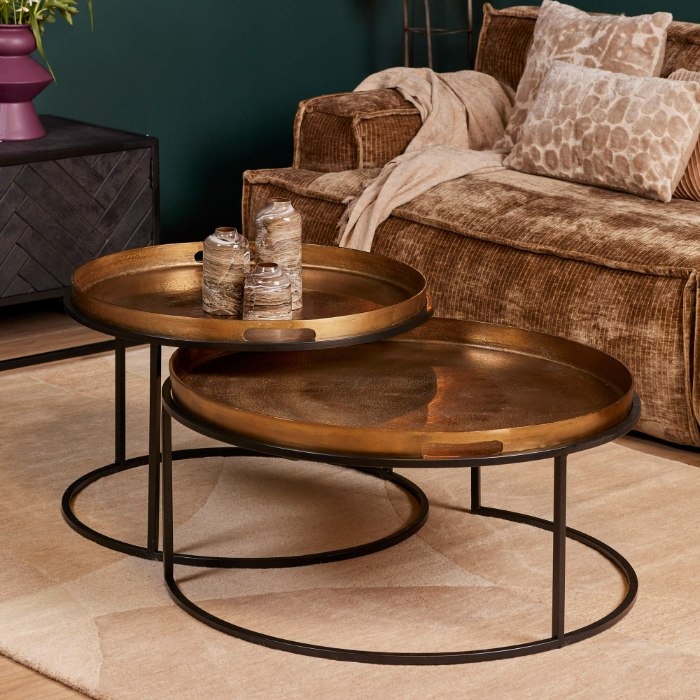 Ronde Puck salontafels in goud naast een fluwelen fauteuil