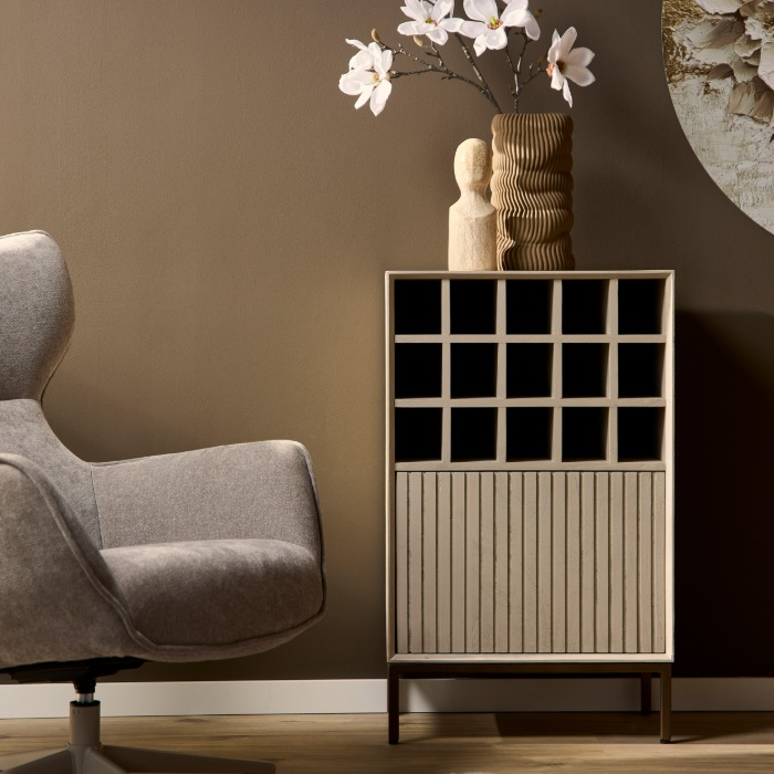 Zandkleurige wijnkast Madison naast een fauteuil in een sfeervol interieur