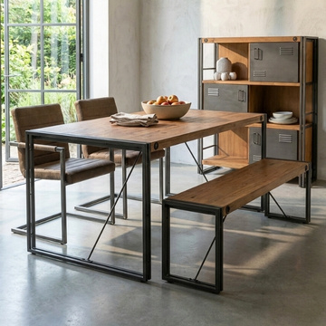 Industriële eettafel met houten blad en zwart metalen frame en bijpassende bank, in een woonkamer met betonvloer naast een industriële kast