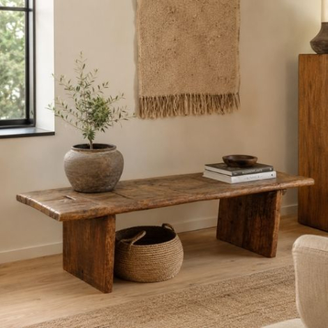 Houten bankje uit India als salontafel in een lichte woonkamer met plant en mand