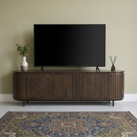 Sfeerfoto van een tv-meubel in walnoot met ronde hoeken van 170 cm in een woonkamer, met een televisie erop, een vaas met plant en wierookstokjes
