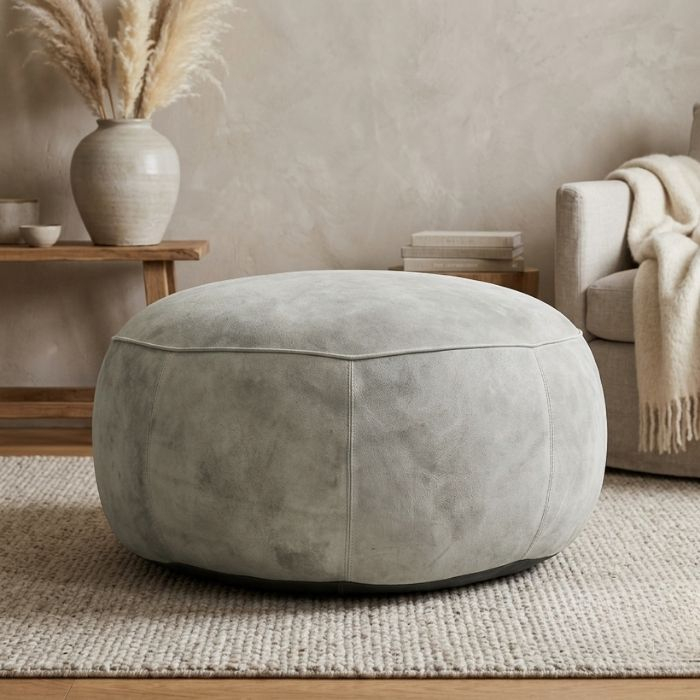 Poef van leer in de kleur lichtgrijs. 